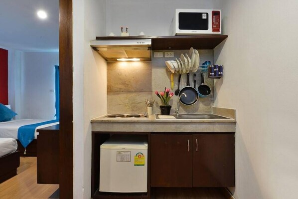 A compact kitchenette with a microwave, stove, and small refrigerator.