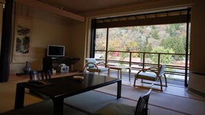 Une pièce de style japonais traditionnel, avec un sol recouvert de tatamis, une table basse et un téléviseur posé sur un meuble.