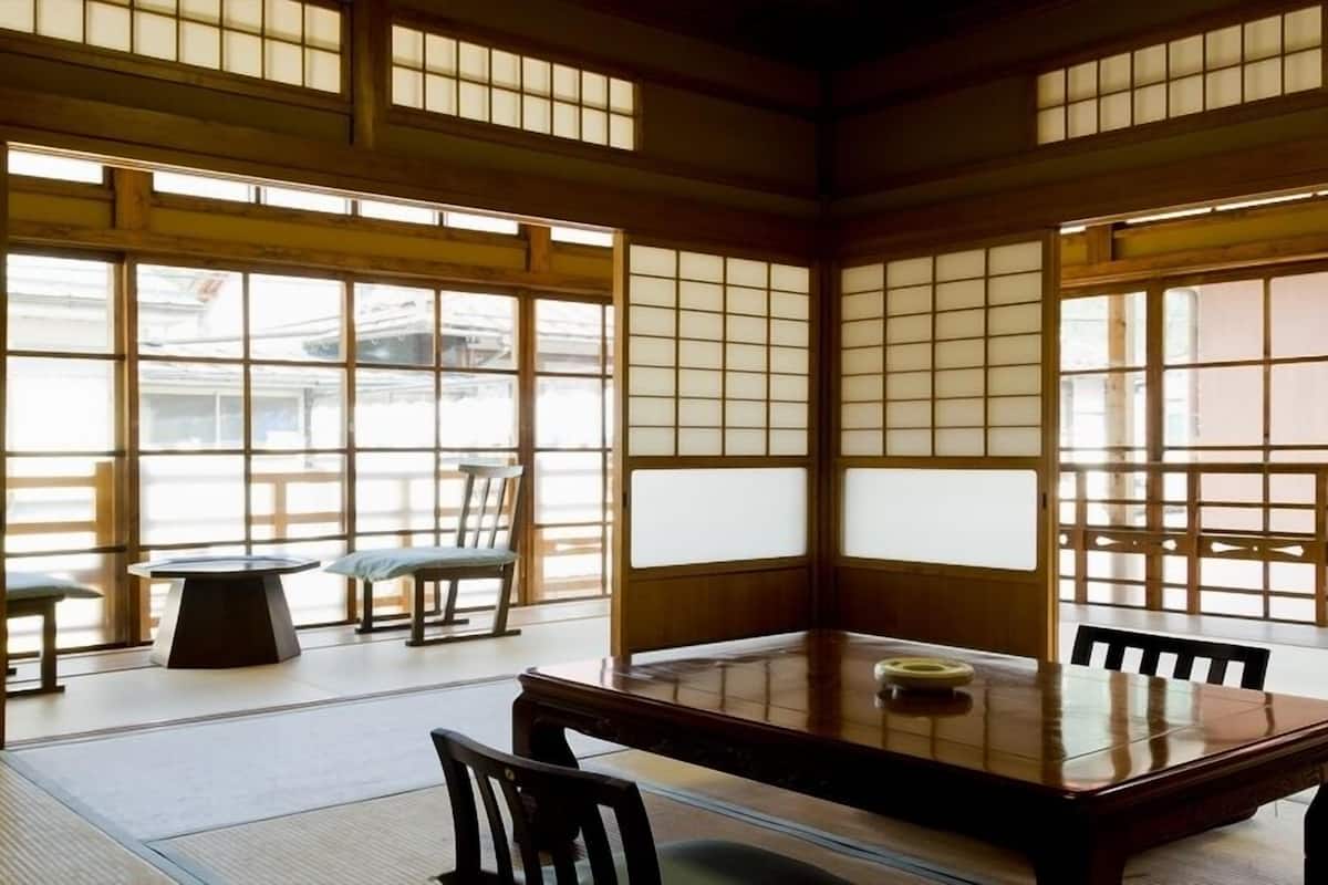 Um quarto japonês tradicional com tatames, uma mesa baixa e portas deslizantes.