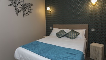 Relax in comfort with a large bed, wall-mounted lighting, and a unique compass-inspired wall art piece.