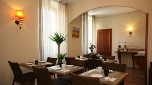 A dining area with tables and chairs, a plant, and a painting on the wall. - Hotel Duc de Padoue (Corte)