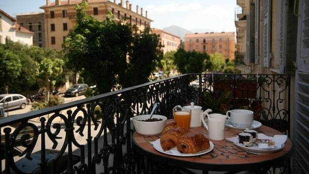 A balcony with a table set for breakfast, including croissants, coffee, and tea. - Hotel Duc de Padoue (Corte)