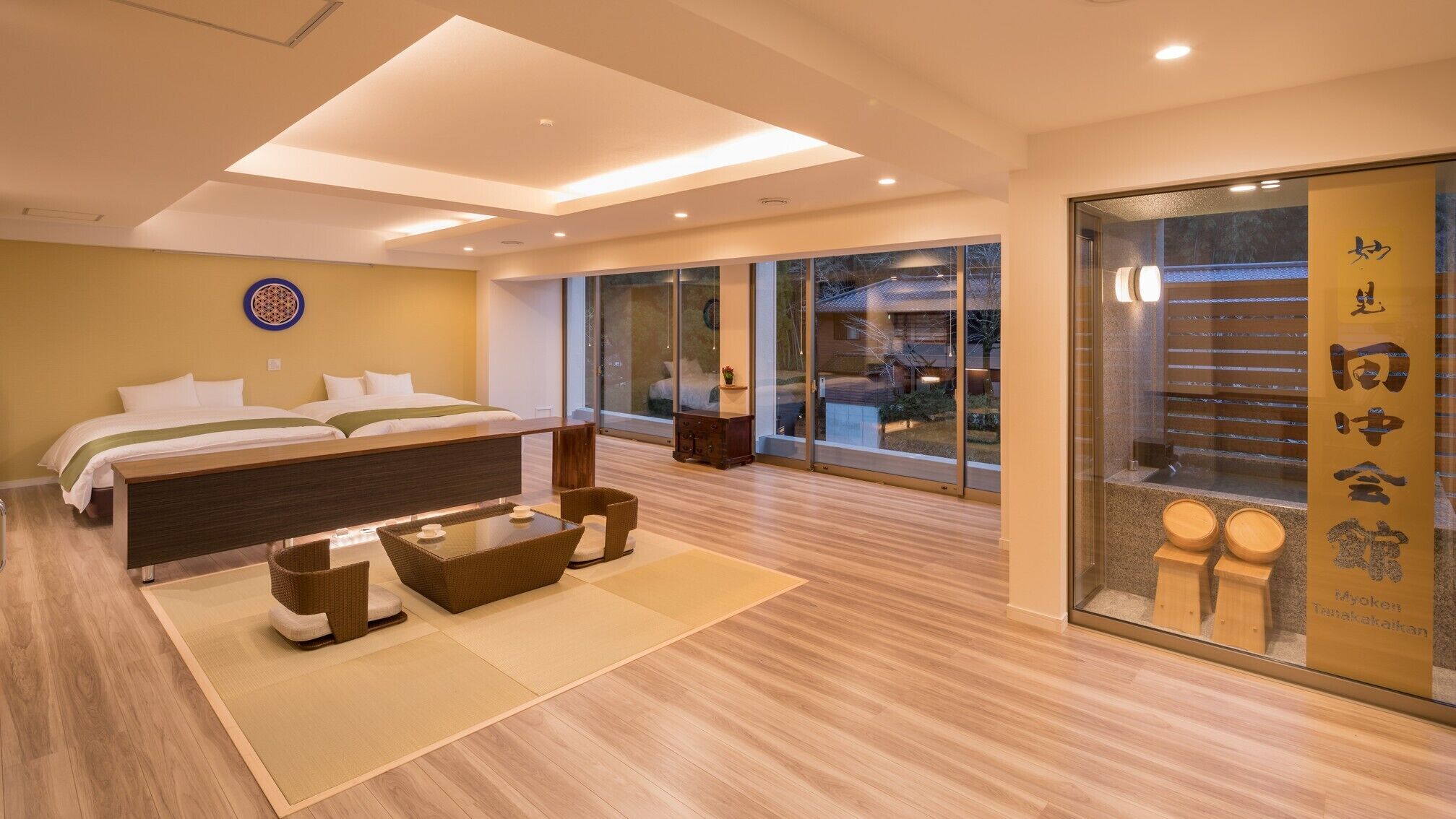 A modern hotel room with a large bed, a small table, and a view of the outside.