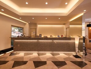 A reception area with a long counter, recessed lighting, and a check-in desk. - Tanaka Kaikan (Kirishima)