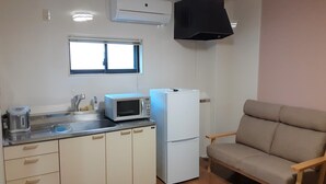 A compact kitchen with a microwave, refrigerator, and a window above the sink. - Hotel Amabile Maizuru (Maizuru)