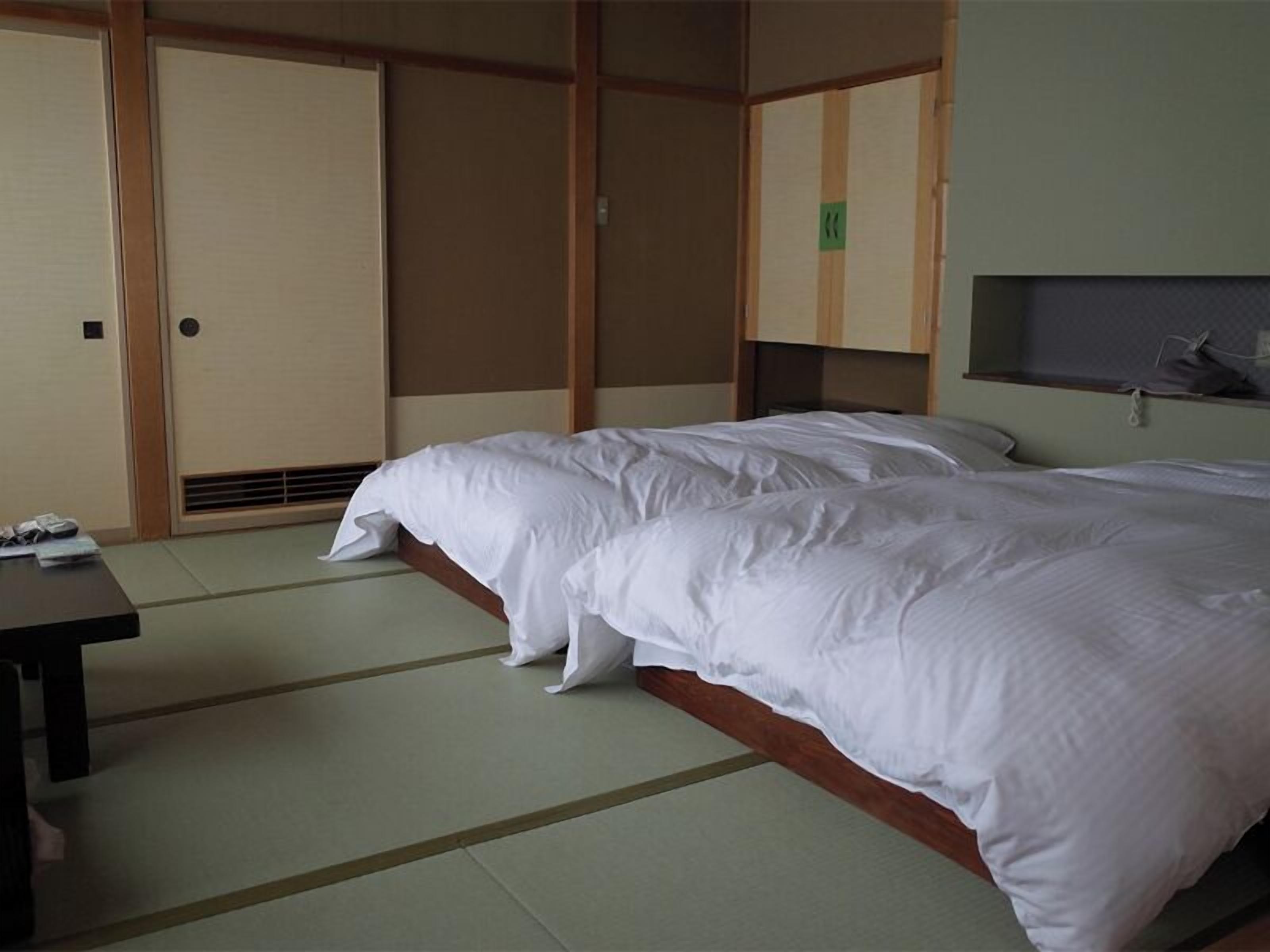 A hotel room with a bed, a desk, and a wardrobe.