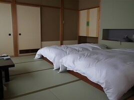 Habitación de hotel con dos camas, suelo de madera, escritorio y armario.