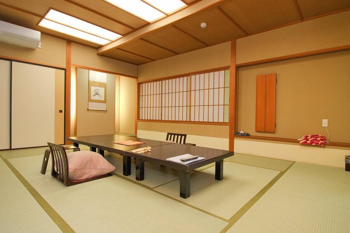 Ein traditioneller japanischer Raum mit Tatami-Bodenbelag, einem niedrigen Tisch und Schiebetüren.