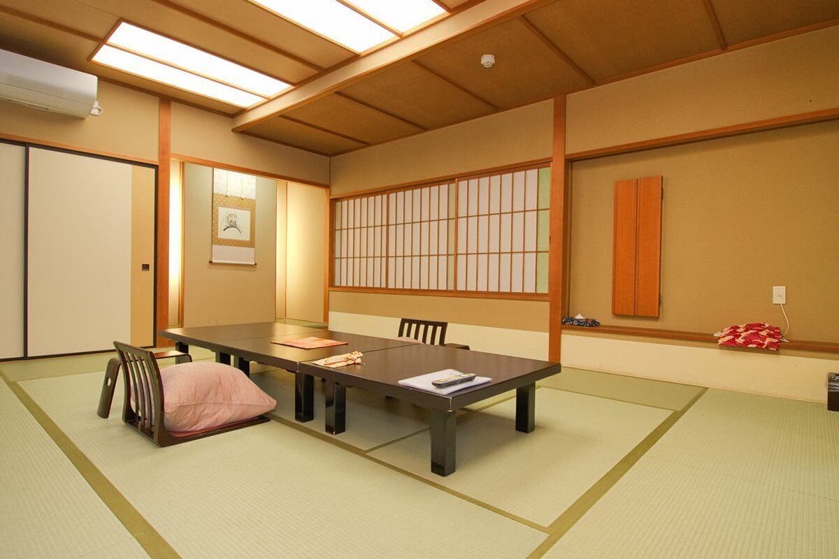 A traditional Japanese room with tatami flooring, a low table, and sliding doors.