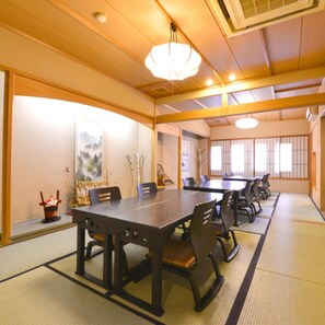 A traditional Japanese-style meeting room with tatami flooring, wooden tables, and chairs.