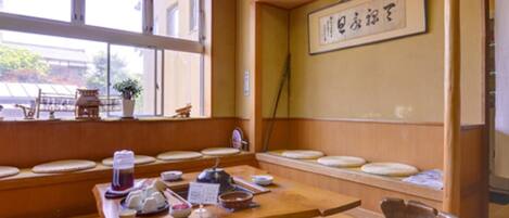 A traditional Japanese room with tatami flooring, a low table with tea utensils, and a shoji screen.