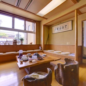 Une pièce de style japonais traditionnel, avec un sol recouvert de tatamis, une petite table basse sur laquelle sont disposés des ustensiles à thé et un paravent shoji.