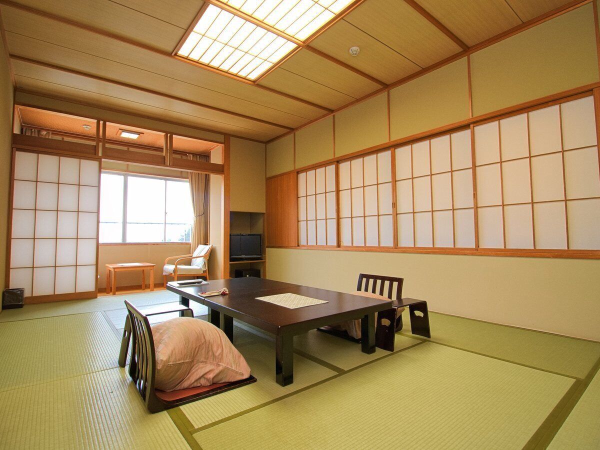 Habitació japonesa tradicional amb tatami, una taula baixa, un sofà i portes corredisses.