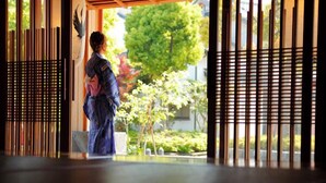 Una habitación japonesa tradicional con suelo de tatami, un biombos shoji y vistas a un jardín.