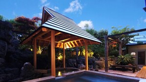 Un área de hidromasaje con un pérgola de madera y una pared de piedra.