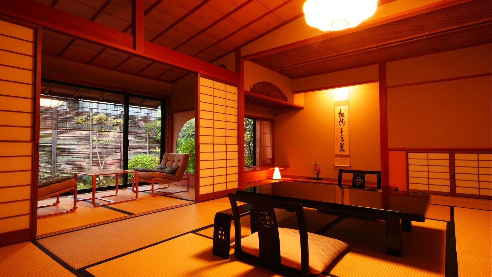 A traditional Japanese room with tatami flooring, a low table, a cushioned chair, and sliding doors.