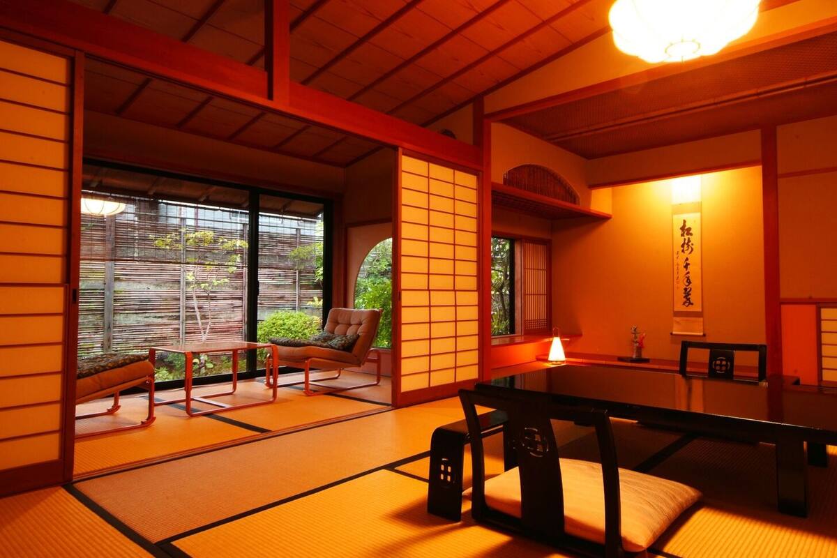 A traditional Japanese room with tatami flooring, a low table, a cushioned chair, and sliding doors.