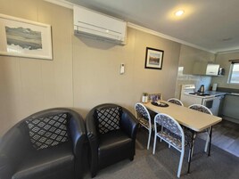 Una habitación compacta con una mesa de comedor, sillas, kitchenette y aire acondicionado instalado.