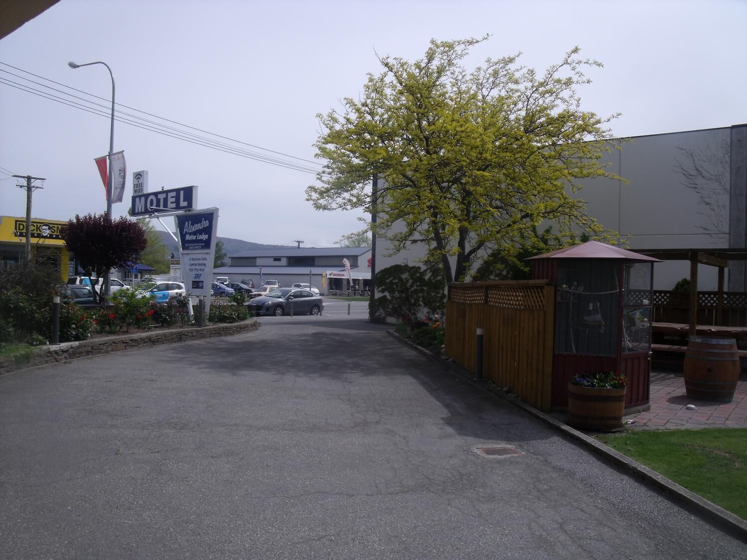 A motel with a signboard, a parking lot, and a building in the background.