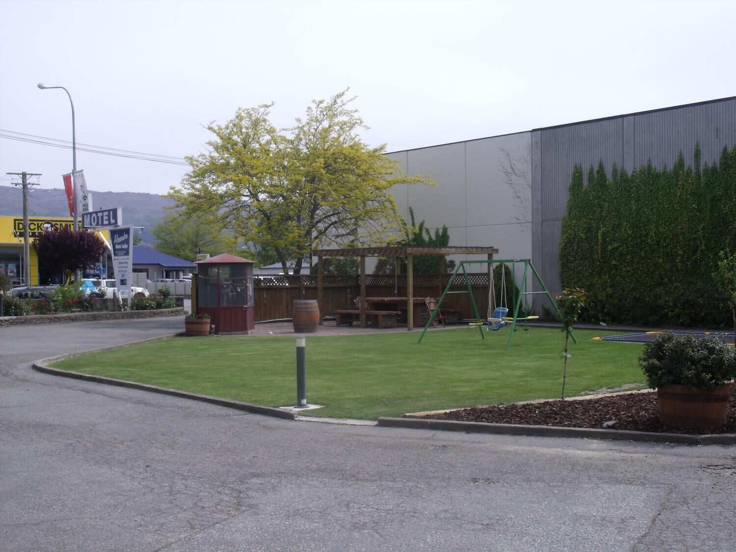 A motel with a playground, a picnic area, and a large building in the background.