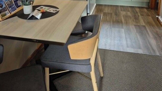 Una cocina compacta con estufa, lavaplatos y armarios, un comedor con mesa y sillas, y un ventanal que proporciona luz natural.