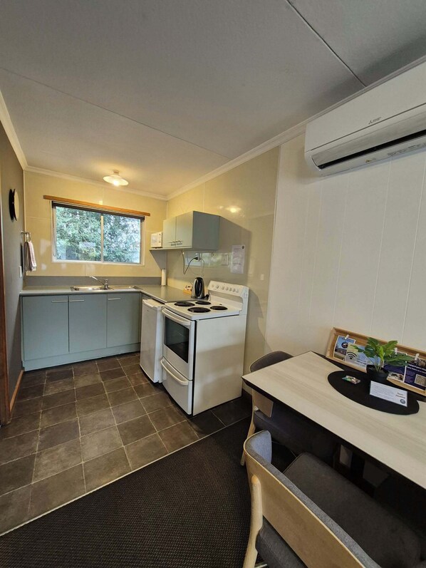 A compact kitchen with a stove, sink, and window.