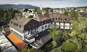A large, multi-story building with a central courtyard, surrounded by trees and other buildings.