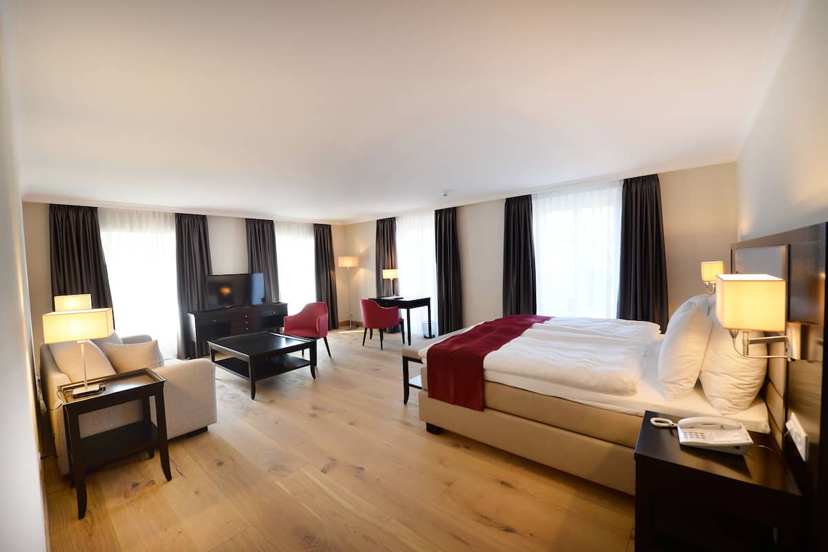 Een hotelkamer met een bed, een bank, een bureau, een televisie en een lamp.
