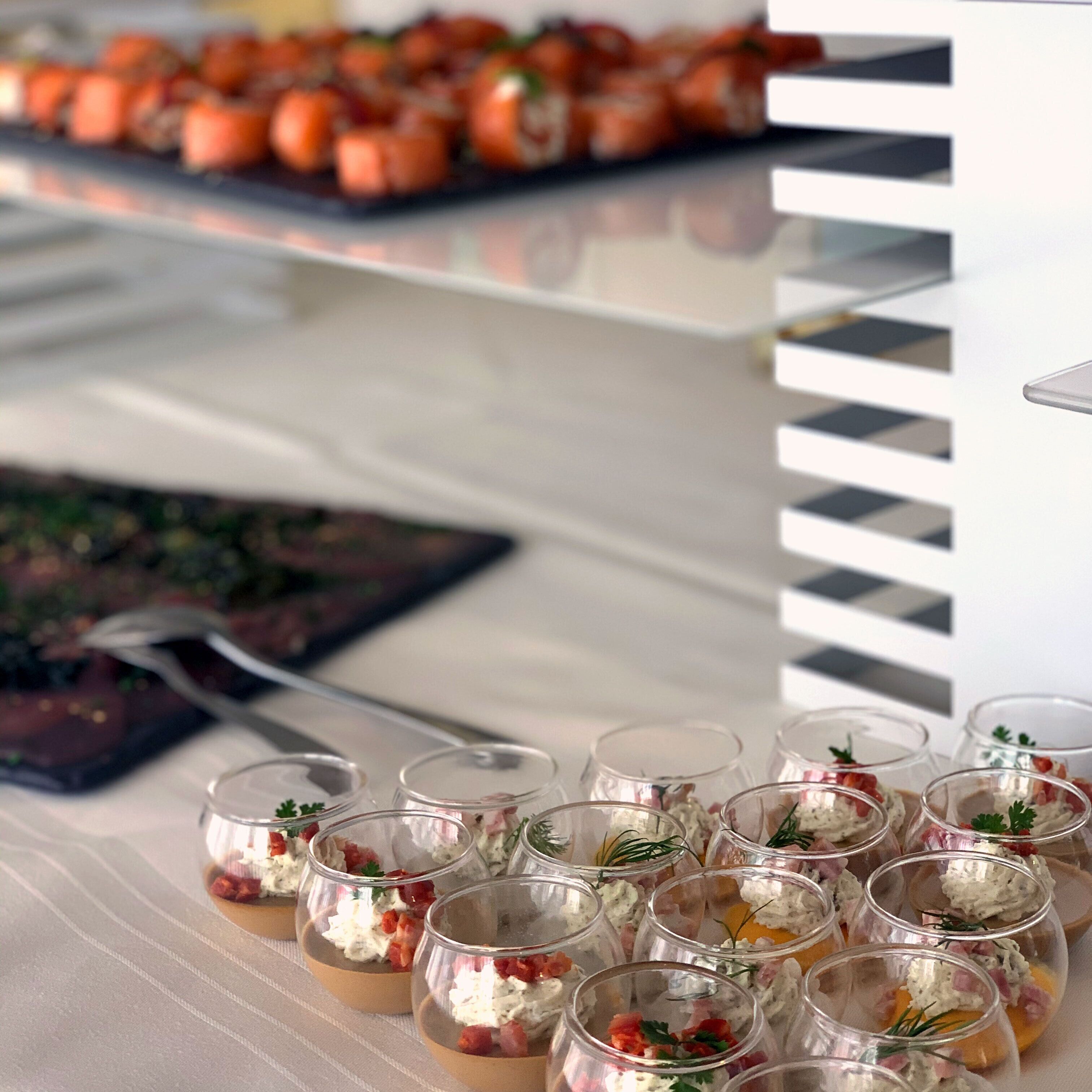 A table with clear glass cups containing food items, possibly appetizers, arranged neatly.