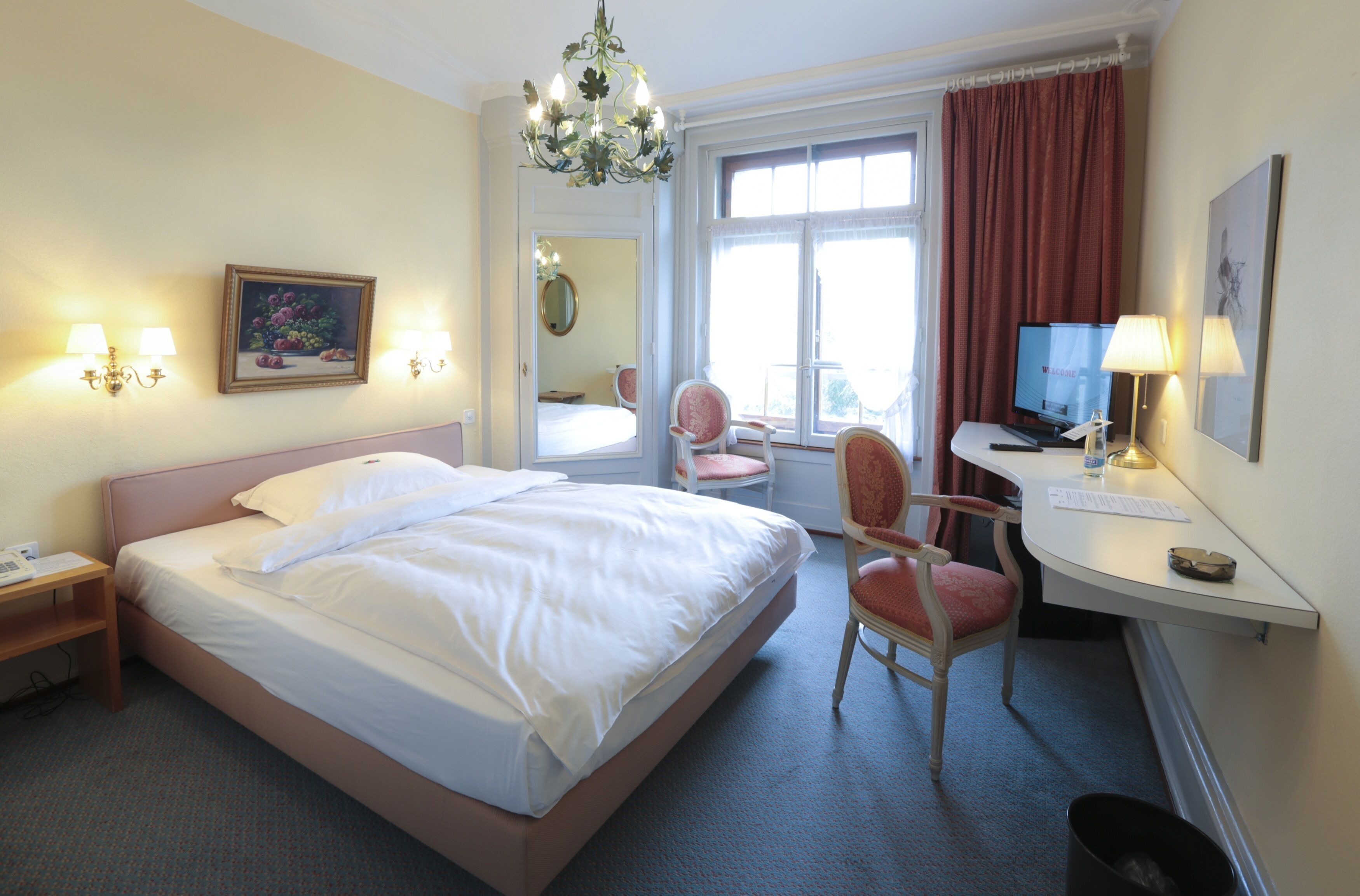 Une chambre d’hôtel équipée d’un lit, d’un bureau, d’une chaise et d’un téléviseur.