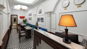 A hotel lobby with a reception desk, seating area, and wall clocks labeled 'Paris' and 'Hanoi'.