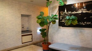 A potted plant in a corner, a small sink with a mirror, and a wall-mounted artwork depicting a traditional scene. - Shirahama Onsen Minshuku A Course (Shirahama)
