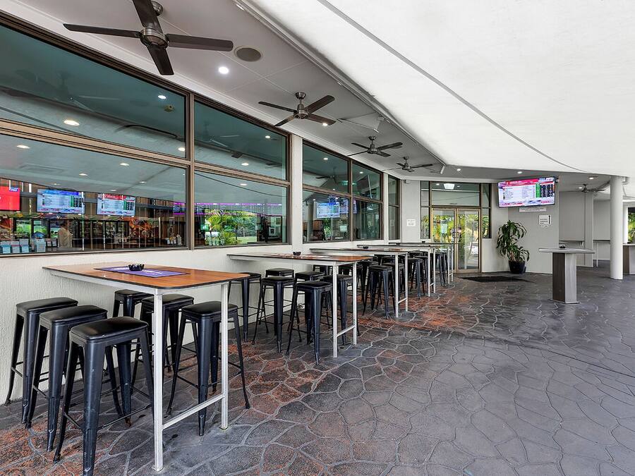 A modern restaurant with high ceilings, ceiling fans, and a stone-tiled floor.