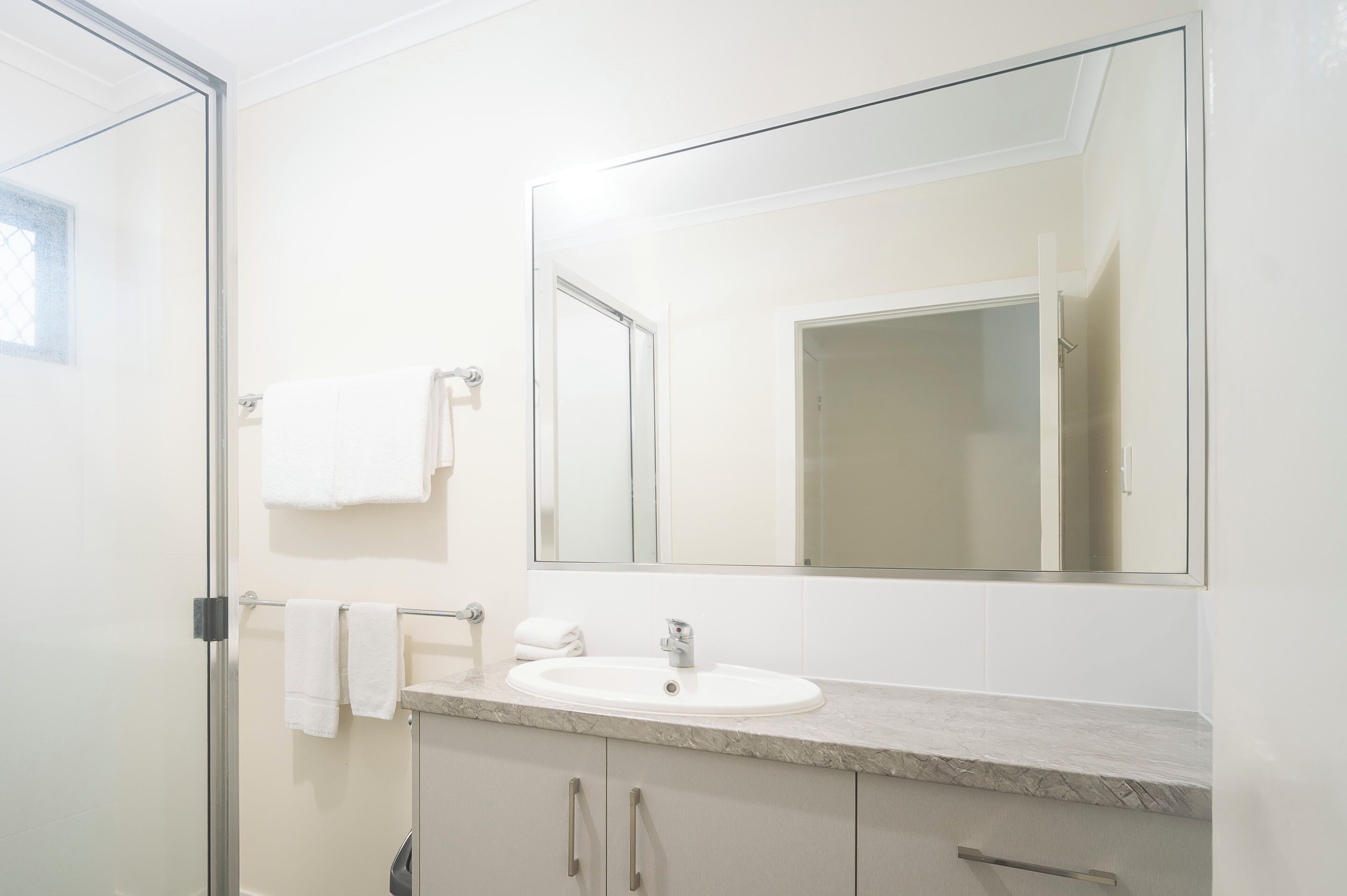 A bathroom with a white sink, a large mirror, and a glass shower enclosure.