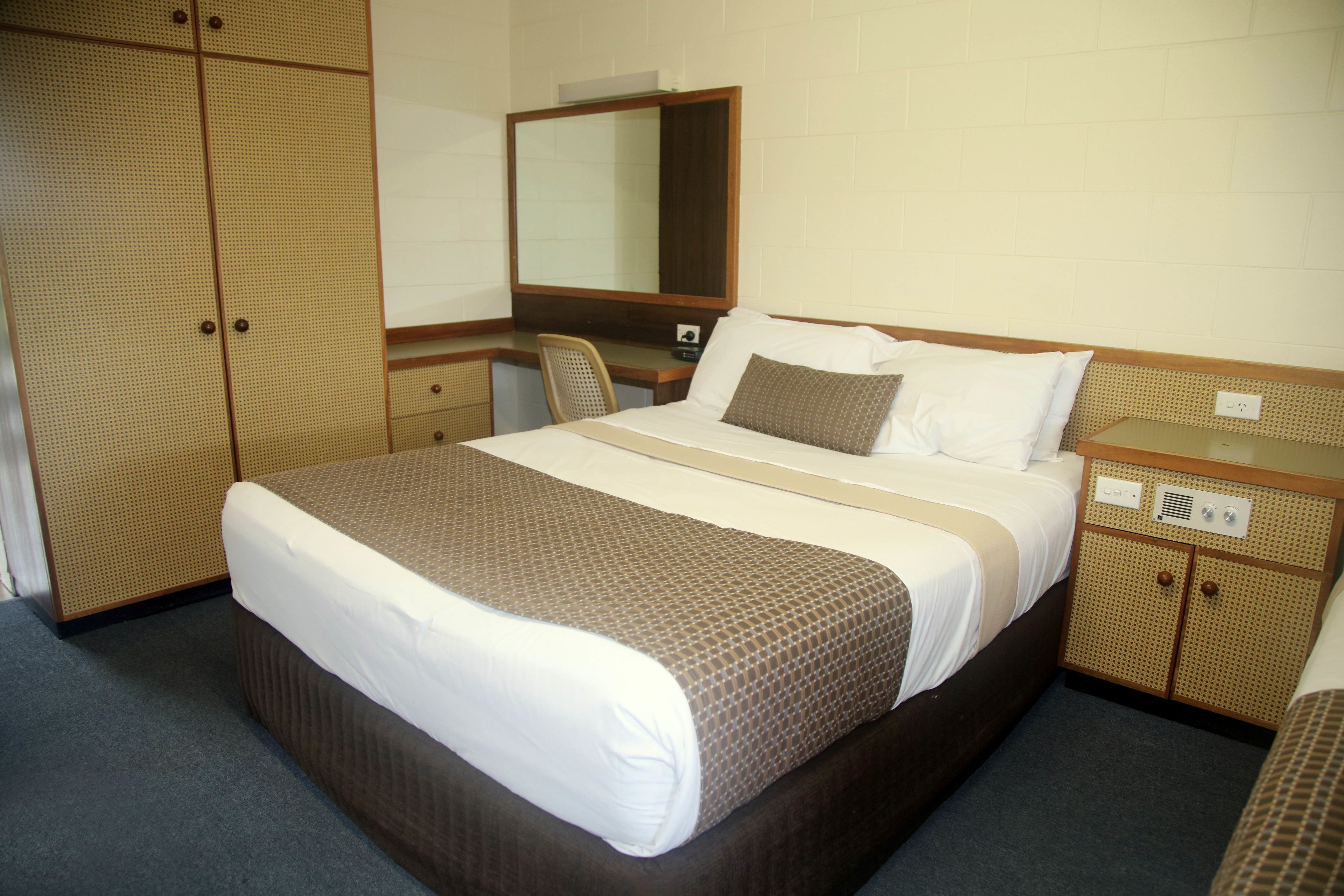 A hotel room with a bed, a desk, a chair, and a wardrobe.
