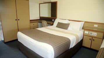 A hotel room with a bed, a desk, a chair, and a wardrobe.