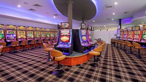 A row of slot machines with a central pillar and bar stools. - Cannonvale Reef Gateway Hotel (Cannonvale)