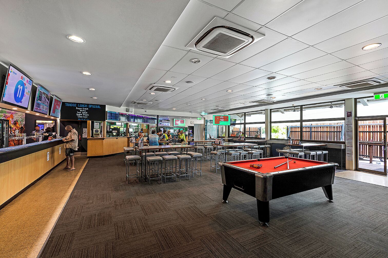 A billiards room with a pool table, bar area, and seating.