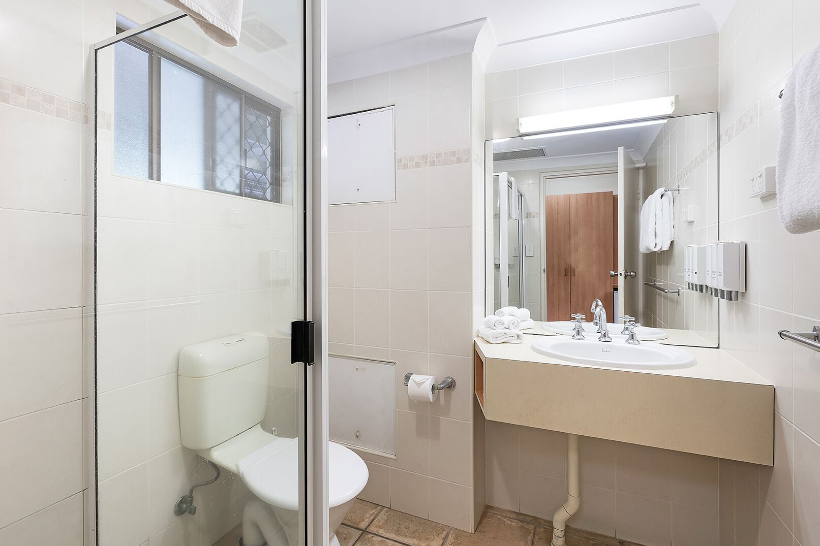 A bathroom with a glass shower enclosure, a toilet, a sink with a mirror, and a towel rack.