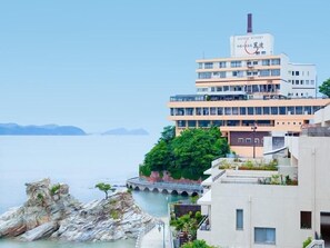 A multi-story hotel with a sign reading 'MANPA RESORT' and a view of the sea.