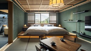A modern bedroom with a large bed, wooden ceiling, and a dining table with chairs. - Yakakutei (Kirishima)