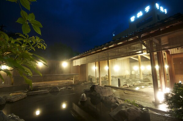 A traditional Japanese onsen with a wooden building and a stone bath area.