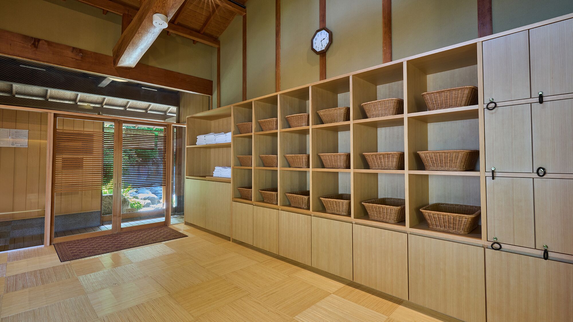A room with wooden flooring, a clock on the wall, and shelves with baskets.
