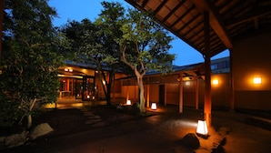 A traditional Japanese-style building with a covered walkway, stone lanterns, and a well-maintained garden. - Yakakutei (Kirishima)