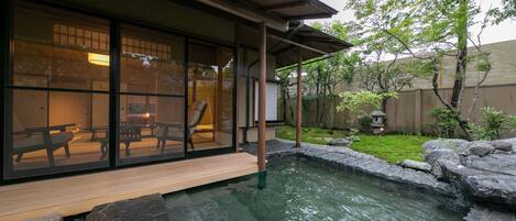 Un edificio de estilo japonés tradicional con un estanque de carpas koi, una terraza de madera y vistas al jardín.