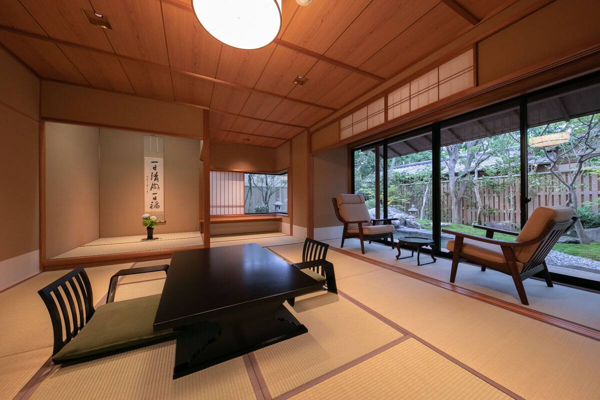 A traditional Japanese-style room with tatami flooring, a low table, and chairs.