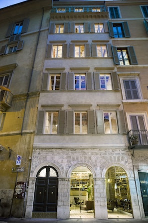 A multi-story building with arched doorways and a ground-floor shop.