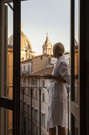 A person standing by a window with a view of a cityscape, including a prominent dome and spire.
