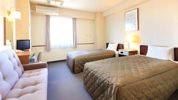 Habitación de hotel con dos camas, un escritorio, una silla, un televisor y una ventana con cortinas.