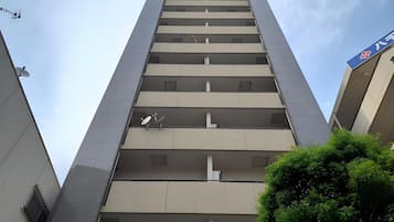 Um edifício alto com várias varandas, uma antena parabólica e uma placa indicando uso comercial.